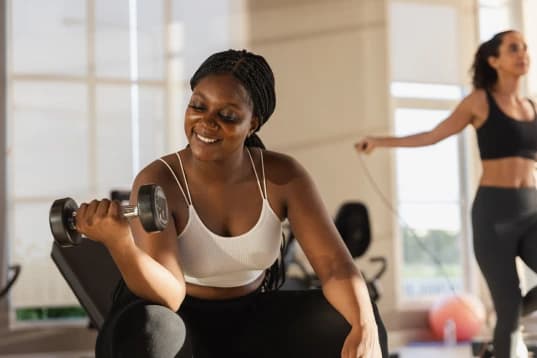 Mulher fazendo exercício com halter A imagem tem uma mulher com roupa de ginástica. Ela está segurando o halter com o braço direito e exercitando-se.
