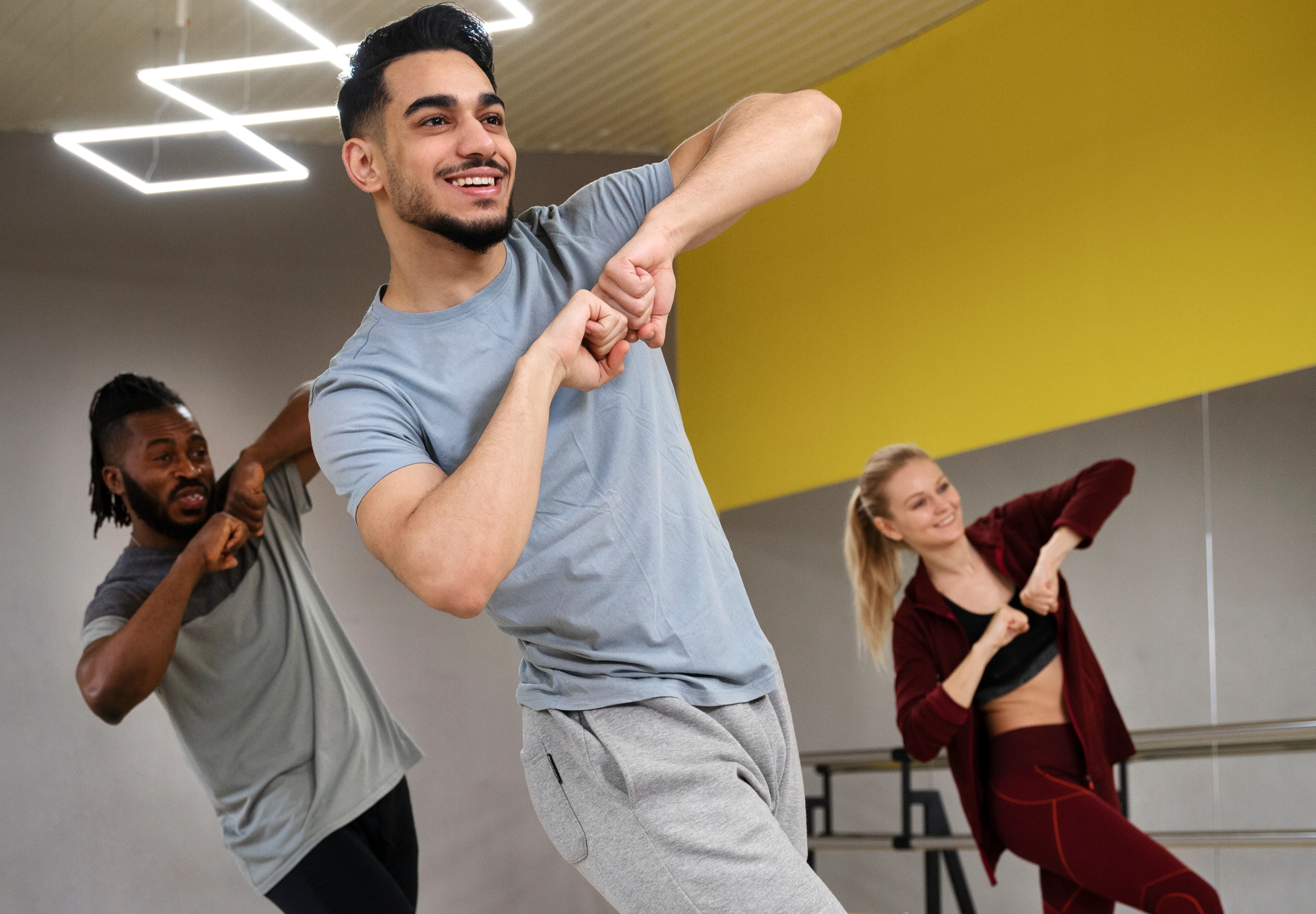 Tres personas tomando clases de baile en un salón de estudio.